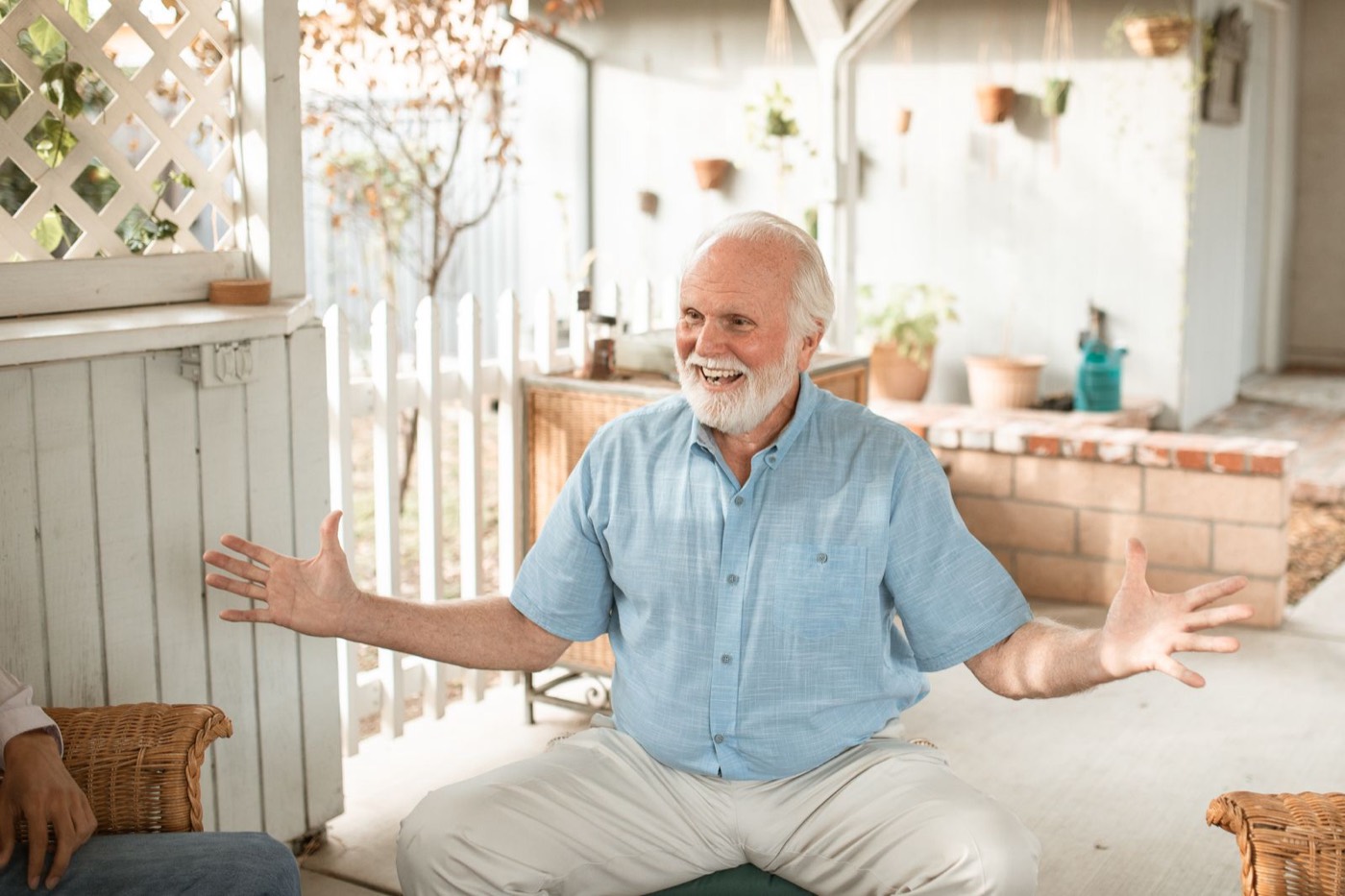 A smiling man welcoming visitors on a bright, tidy patio